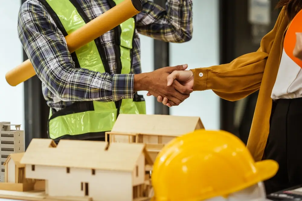 Un homme d'âge mûr, une jeune femme et d'autres personnes d'origine asiatique collaborent à l'ingénierie architecturale de copropriétés et d'appartements.